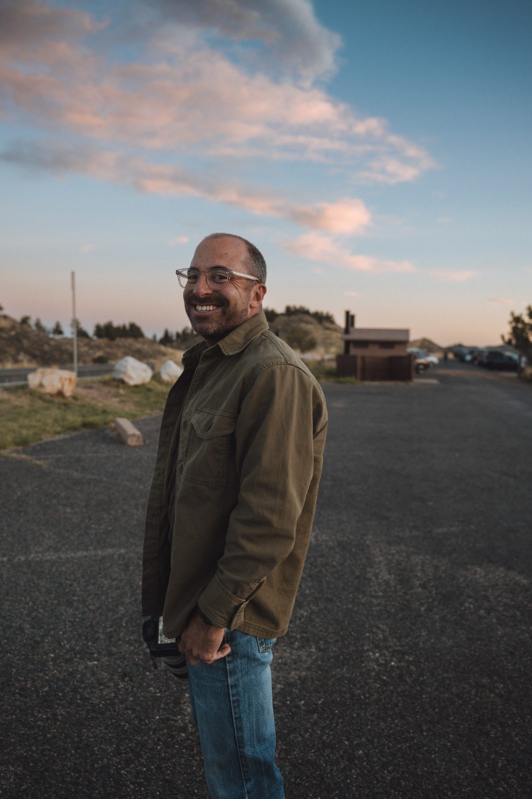Charlie Roberts in an empty overlook pull-out at dusk, camera in hand